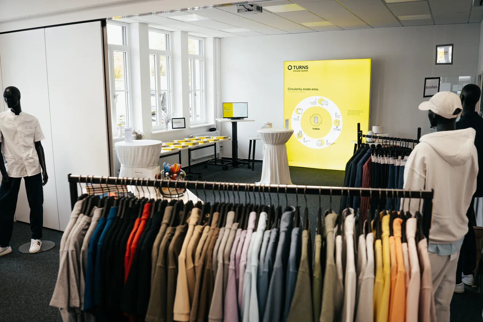 Marktplatz der Möglichkeiten: Kleiderständer mit Arbeitskleidung aus recycelten Fasern